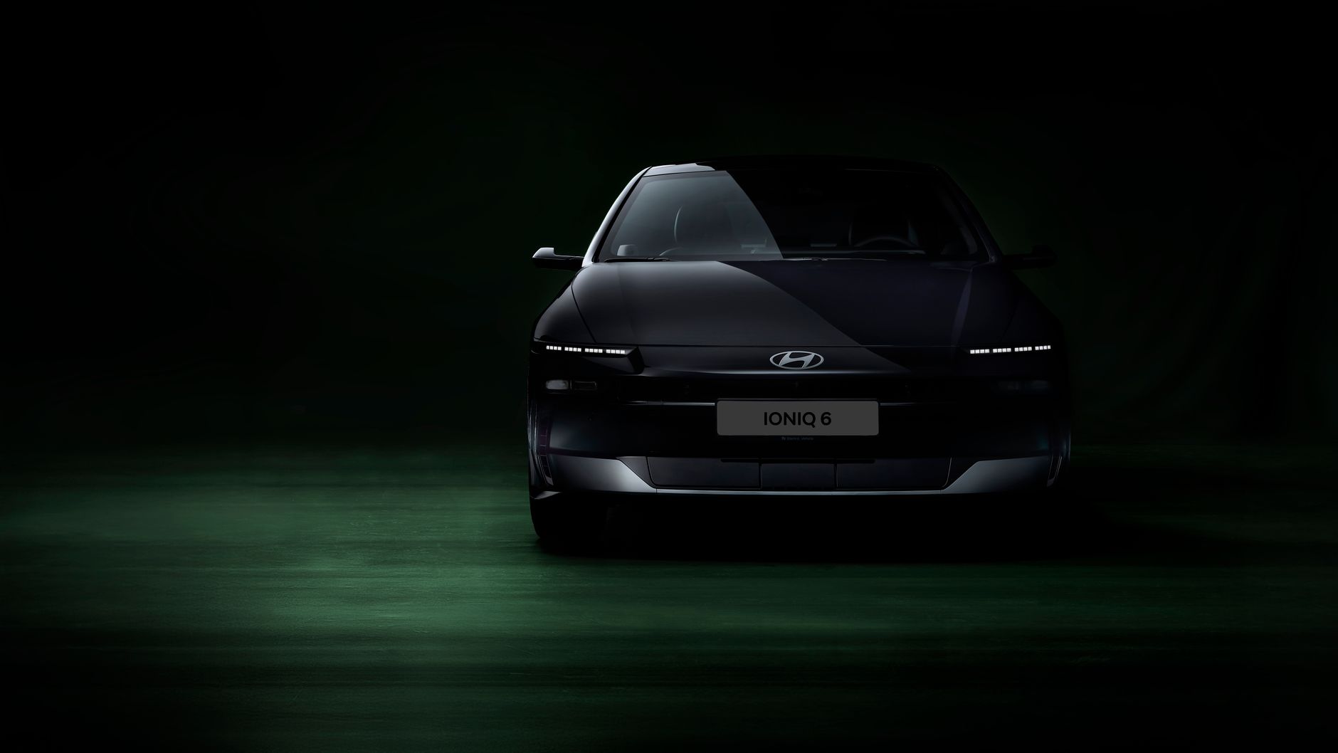 Front view of Hyundai Ioniq 6 electric car in a dimly lit studio setting, highlighting its sleek design.