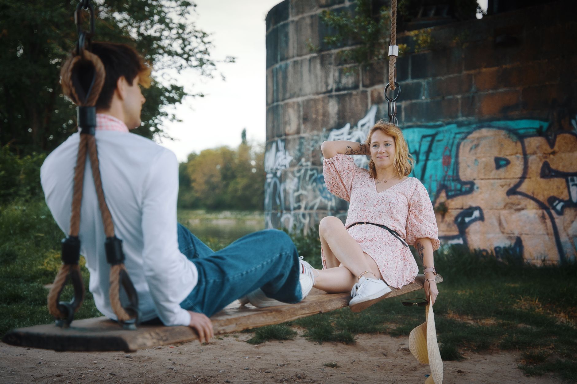 A couple enjoys a calm summer afternoon on a swing in a graffiti-covered park in Magdeburg, Germany.