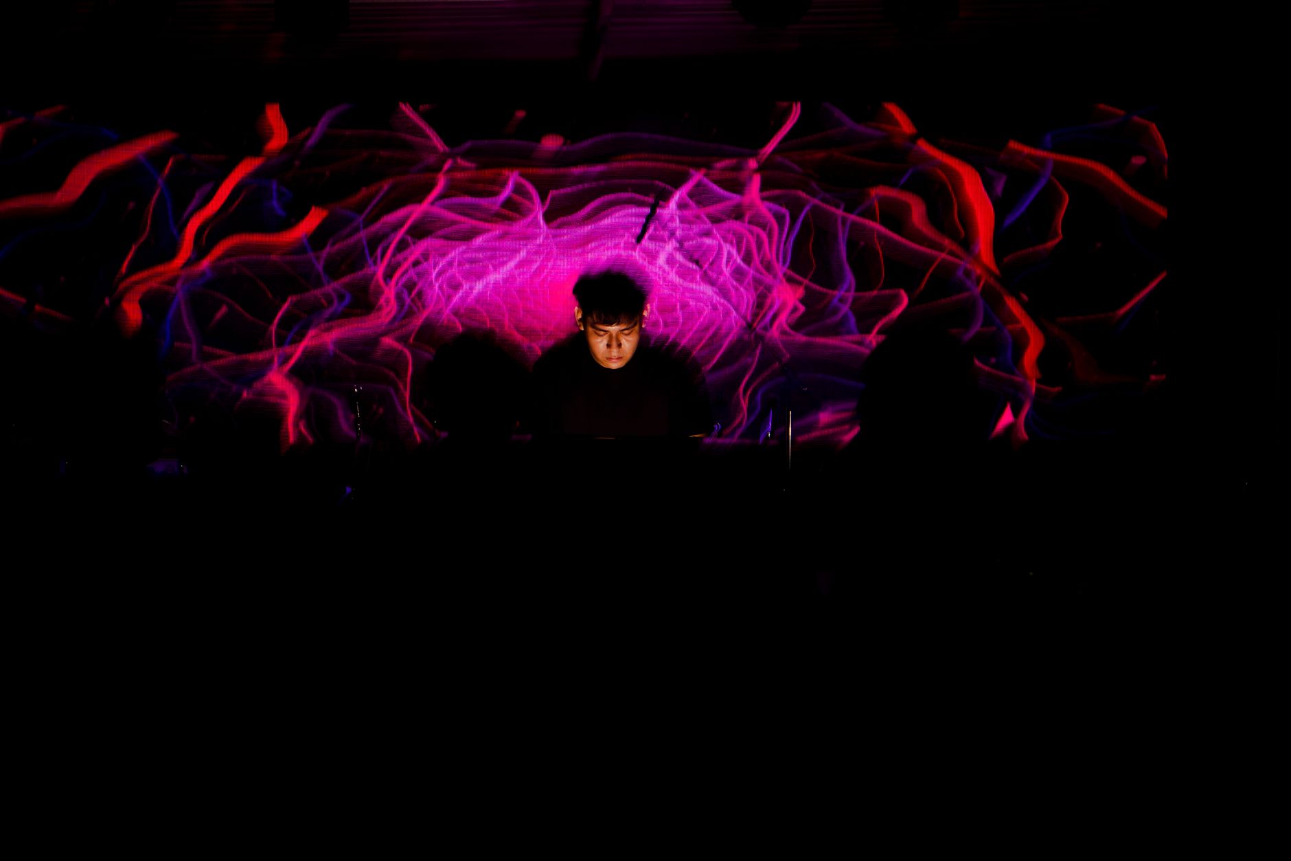 DJ performing with dynamic light display creating vibrant patterns at a party.