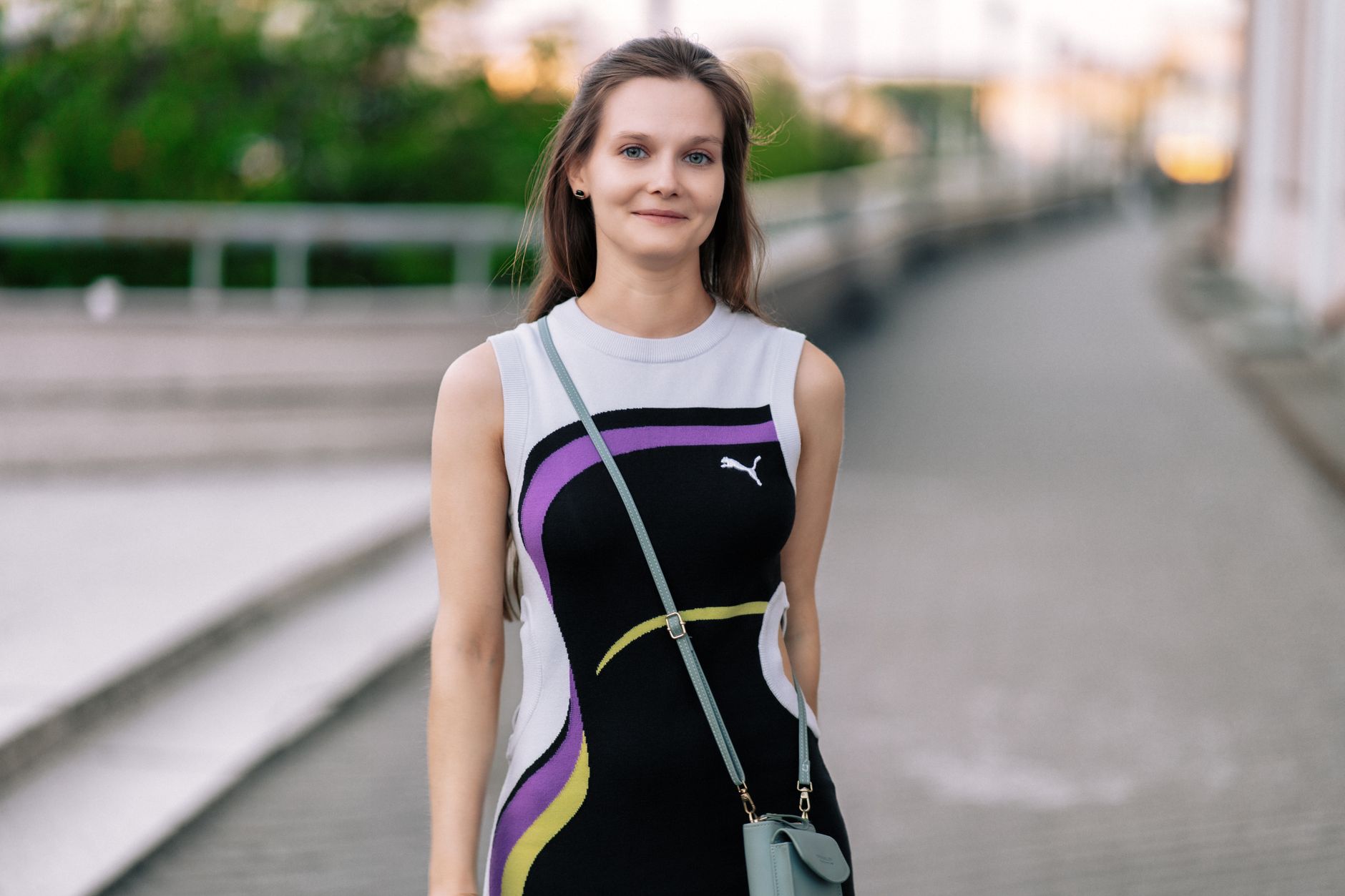Woman posing outdoors in a modern dress, showcasing urban fashion style.