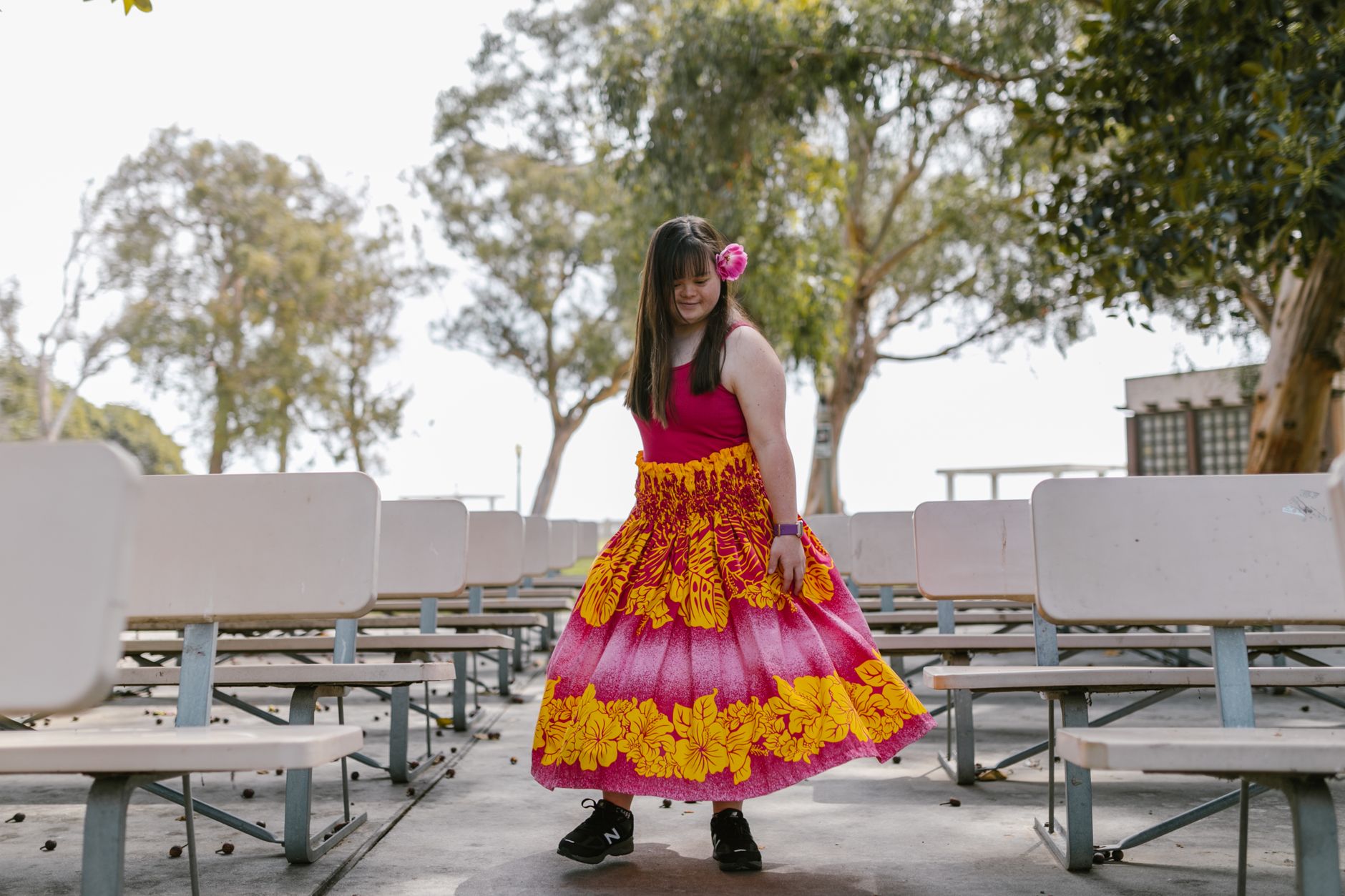Young girl wearing a colorful dress with floral patterns in an outdoor park setting, enjoying a carefree moment.