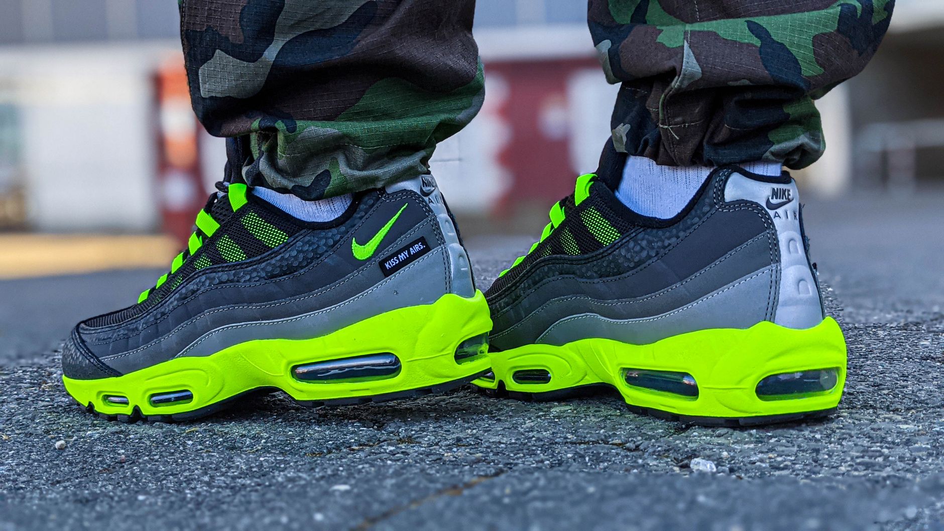Detailed shot of trendy neon green Air sneakers paired with camo pants on an urban street.