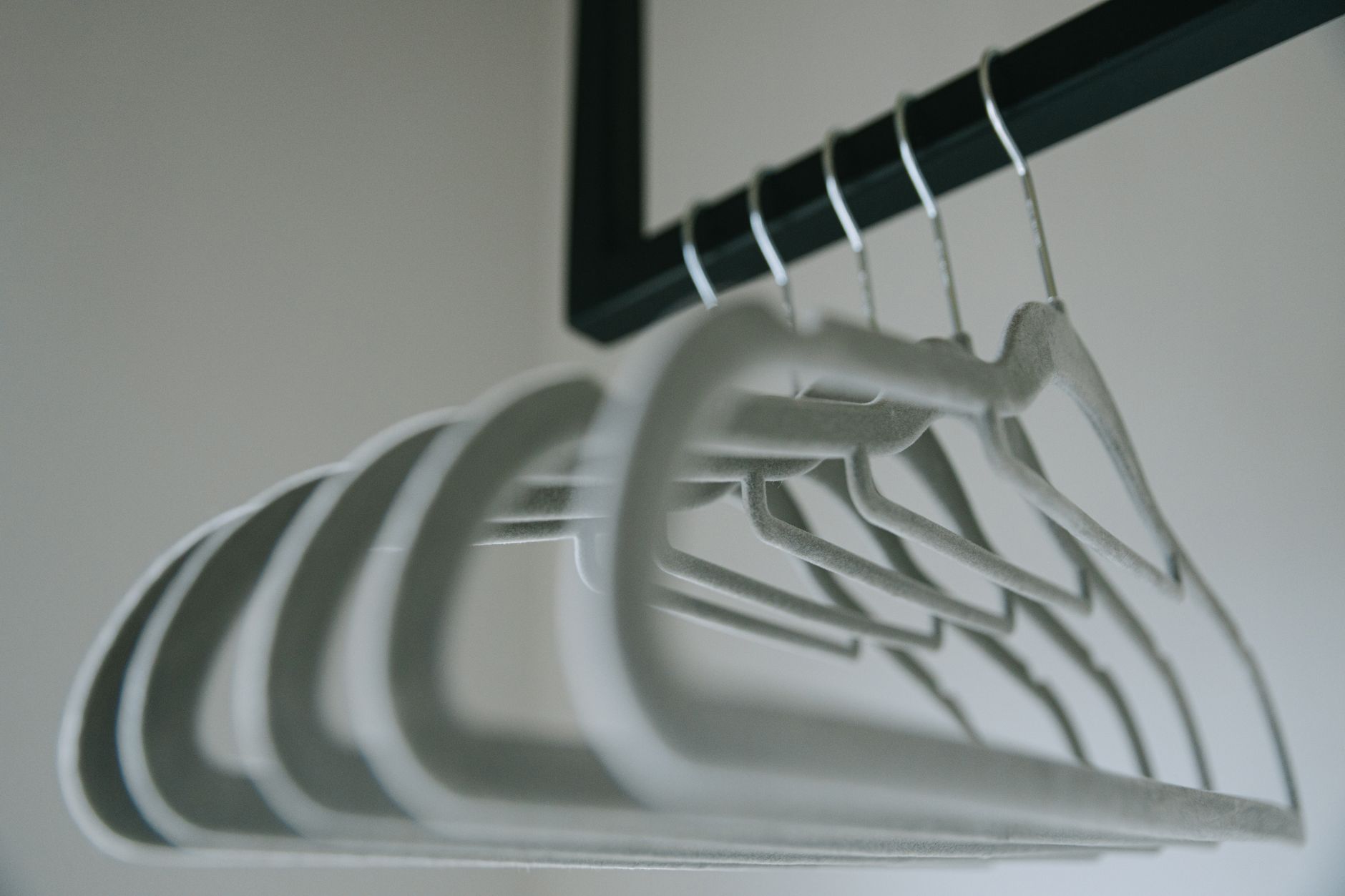 Close-up view of minimalist felt coat hangers on a clothes rack, showcasing simple design.