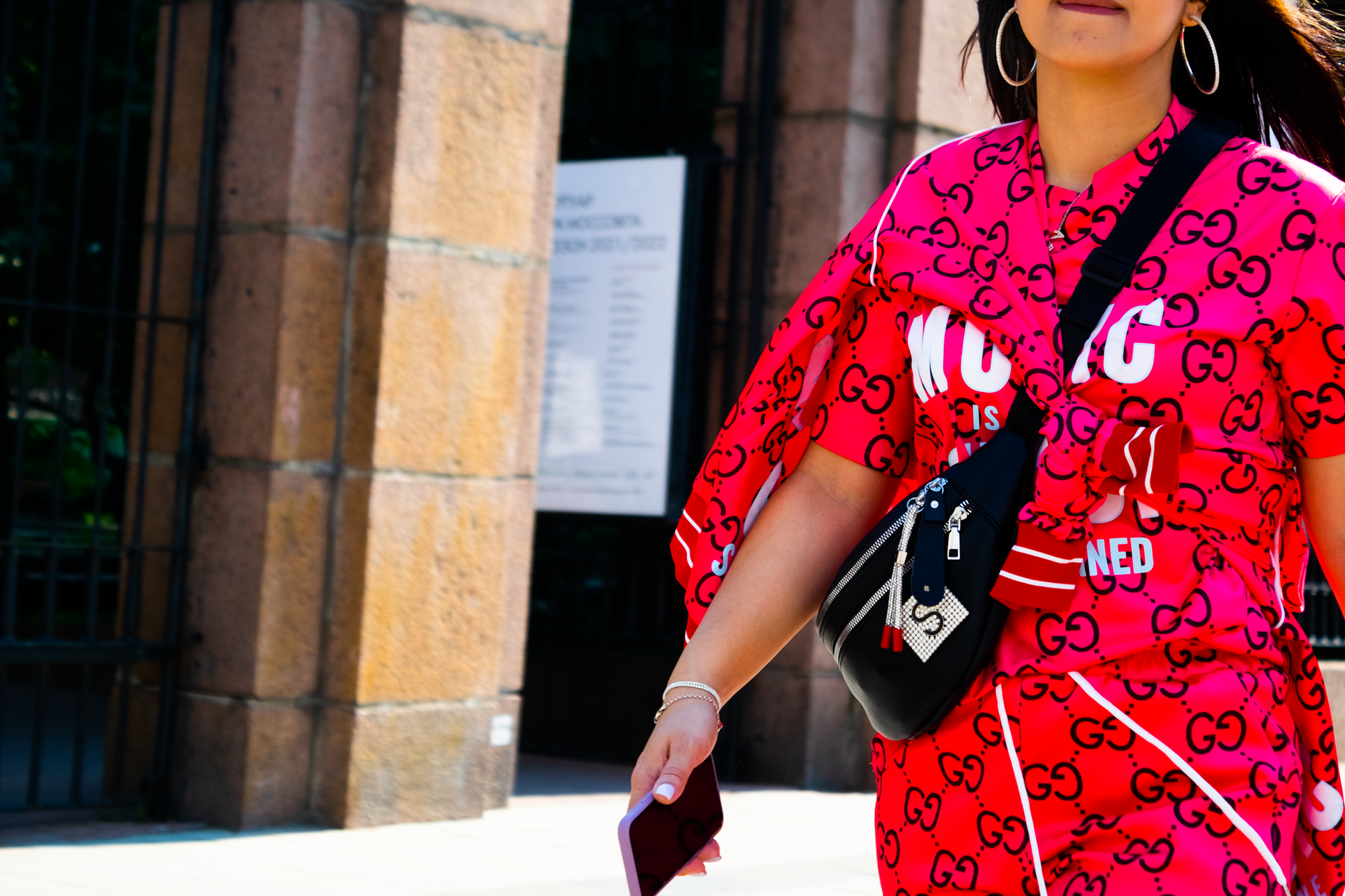Fashionable woman in vibrant red designer outfit strolling outdoors with confidence.