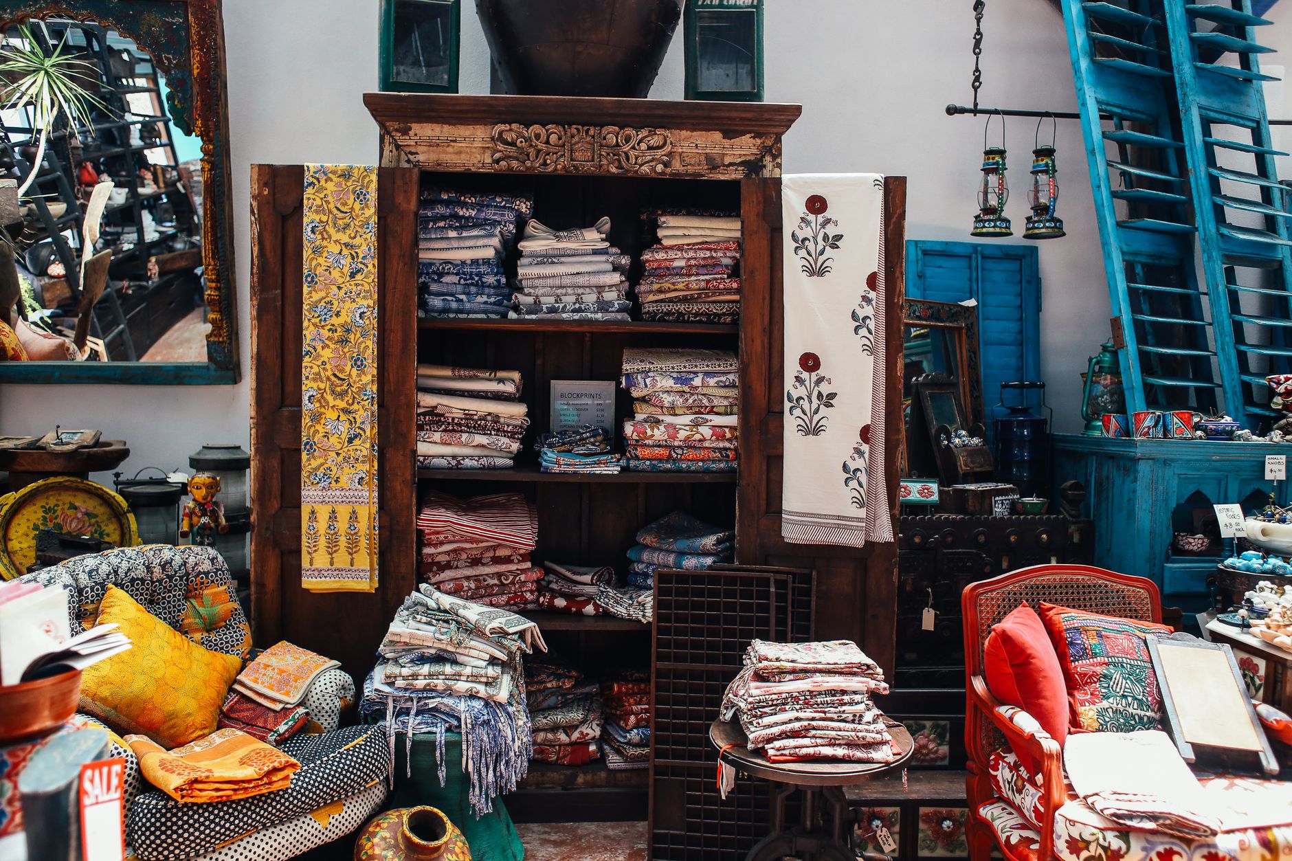 An intricate display of colorful textiles and home decor in a vintage store interior setting.