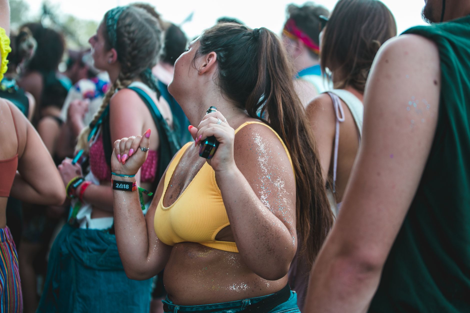 Young adults dancing at an outdoor summer festival, enjoying music and lively atmosphere.