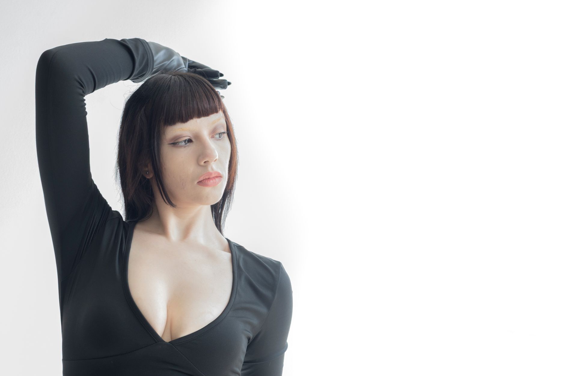 A woman strikes a pose in a sleek black dress against a minimalist white background.