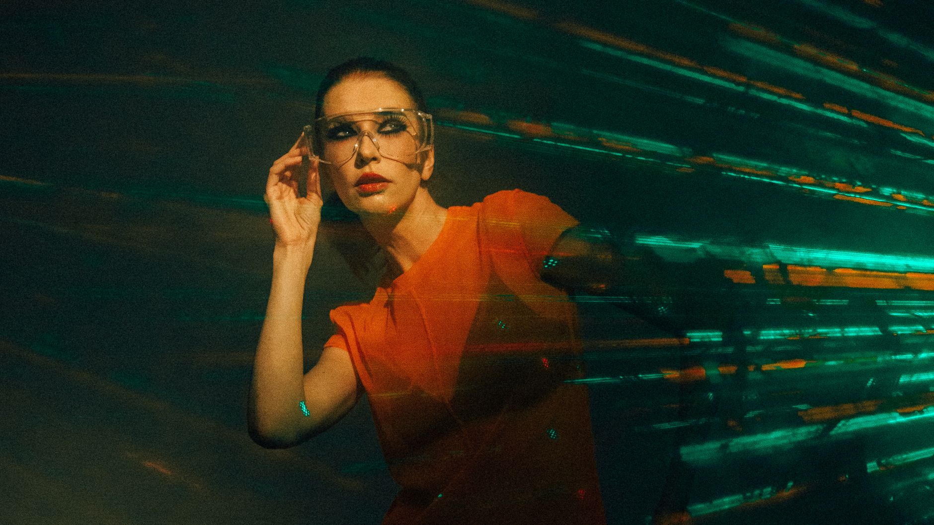 Stylized portrait of a woman in neon light with motion effects, wearing futuristic fashion and eyewear.