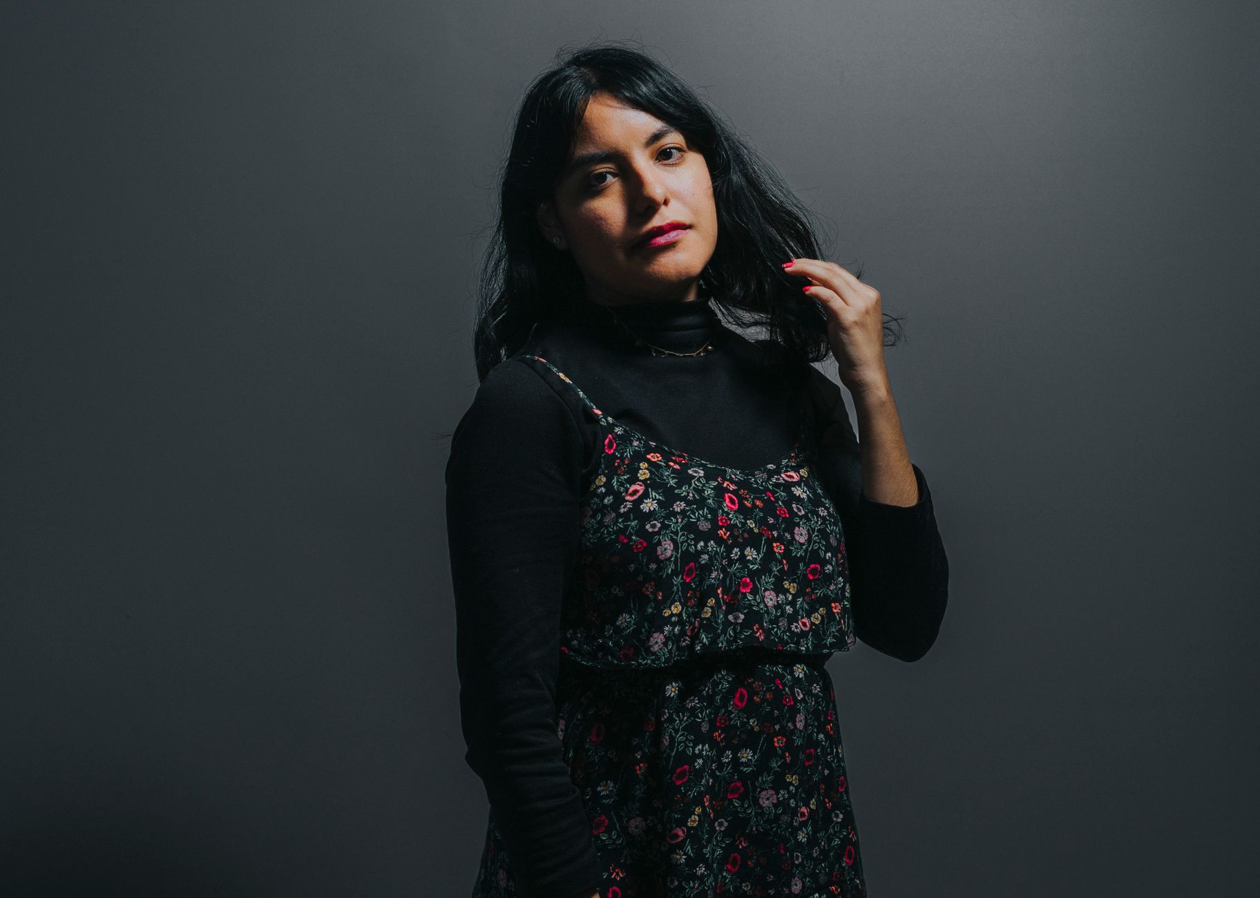 Elegant portrait of a woman in a floral dress with a dark background.