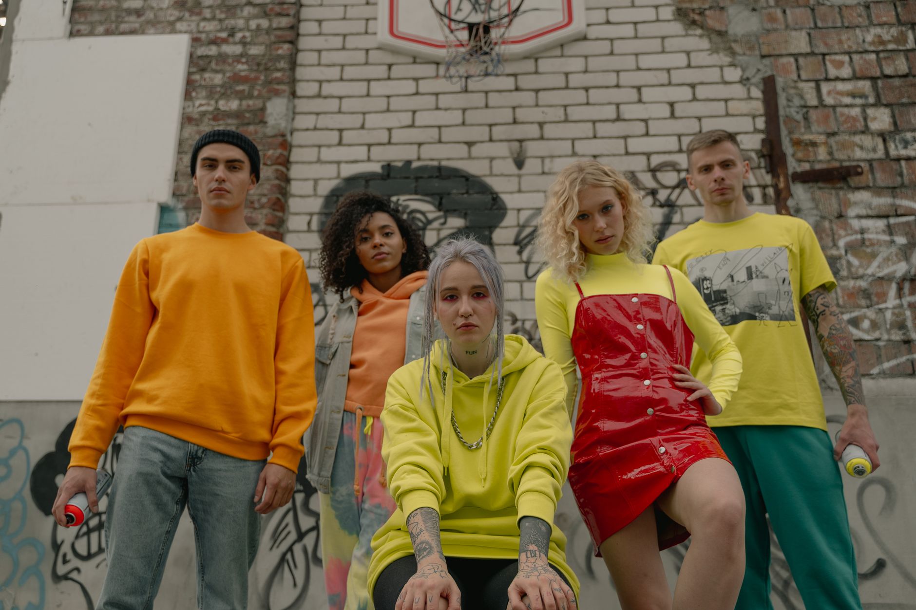 Diverse group showcasing bold street fashion against a graffiti-covered wall.