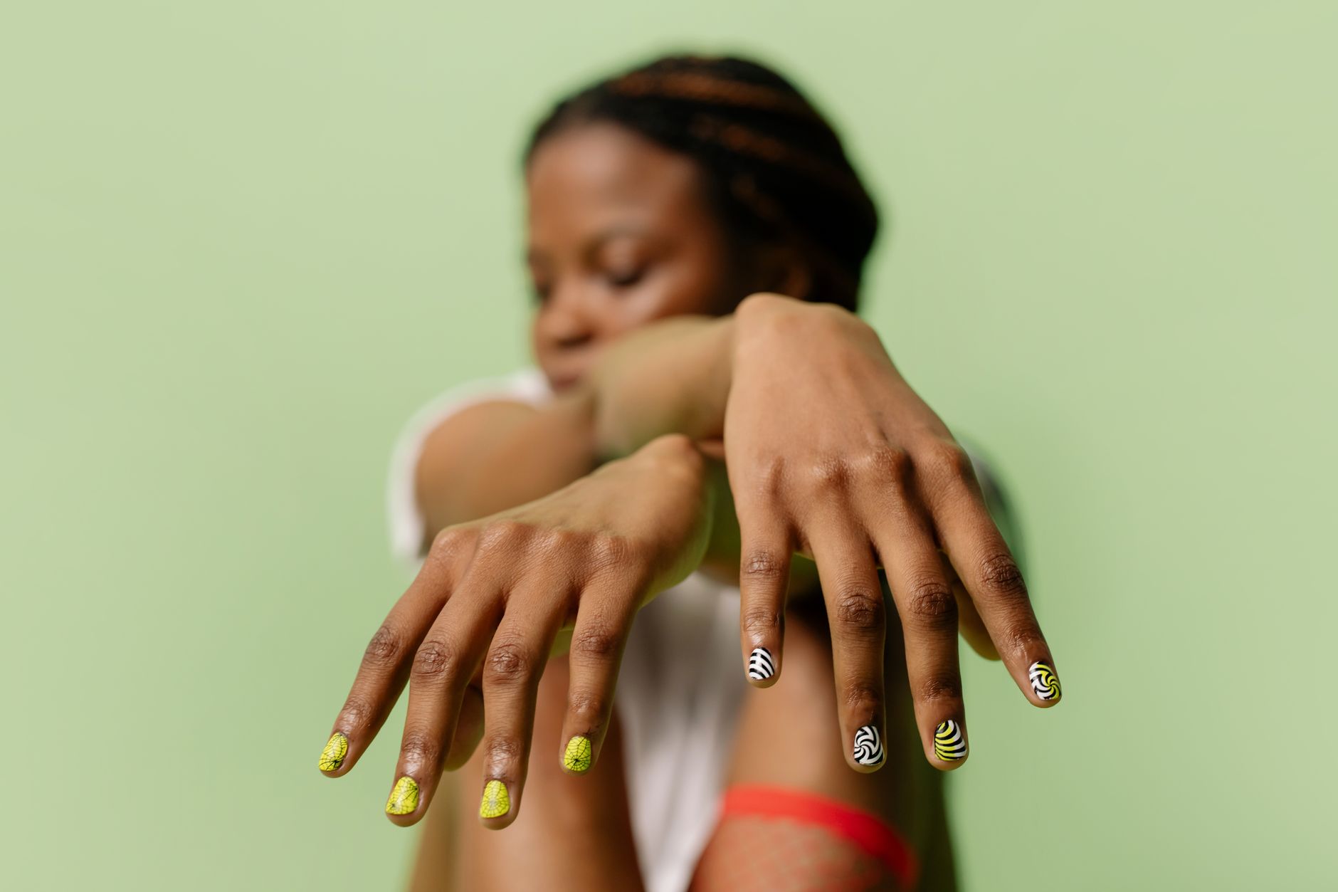 A close-up shot of a woman showcasing intricate nail art designs with a soft green backdrop.