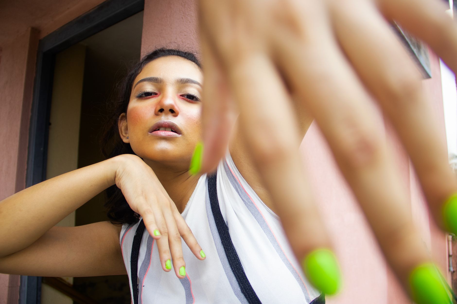 Close-up of a woman posing with neon green nails, showcasing modern fashion.