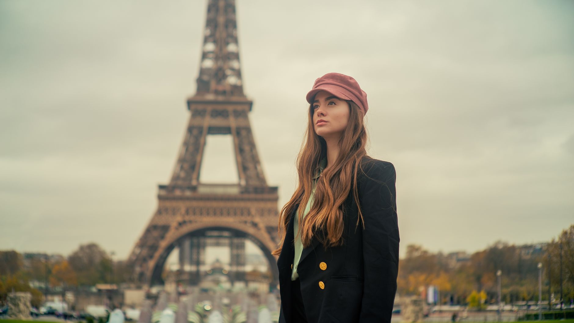 Elegant young woman in Paris posing with a chic look by the Eiffel Tower.