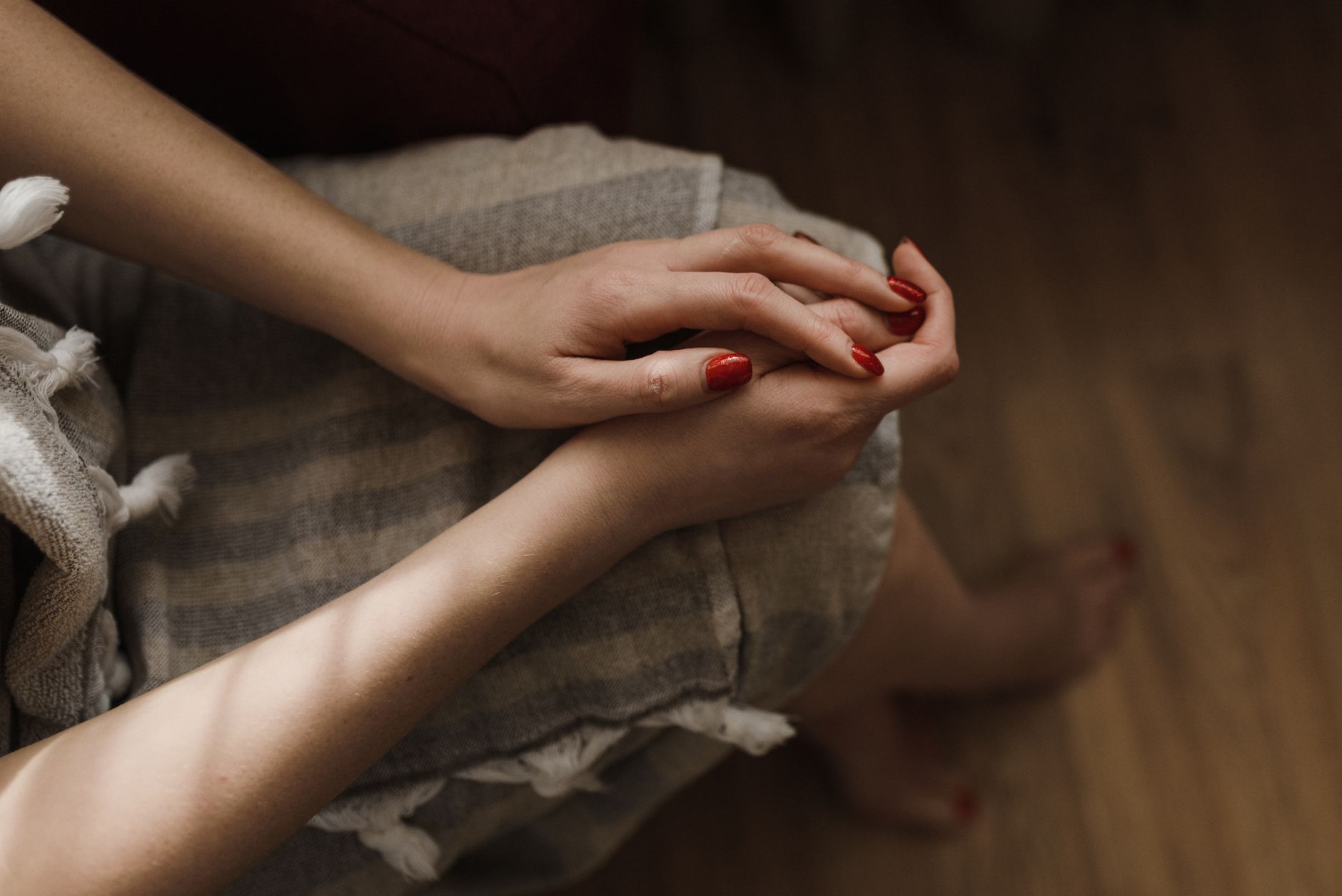 Close-up of hands with red manicured nails in soft natural light, adding a touch of elegance.