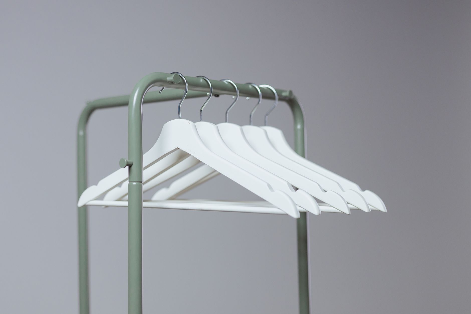 A minimalist indoor clothes rack featuring white hangers with a soft-neutral tone.