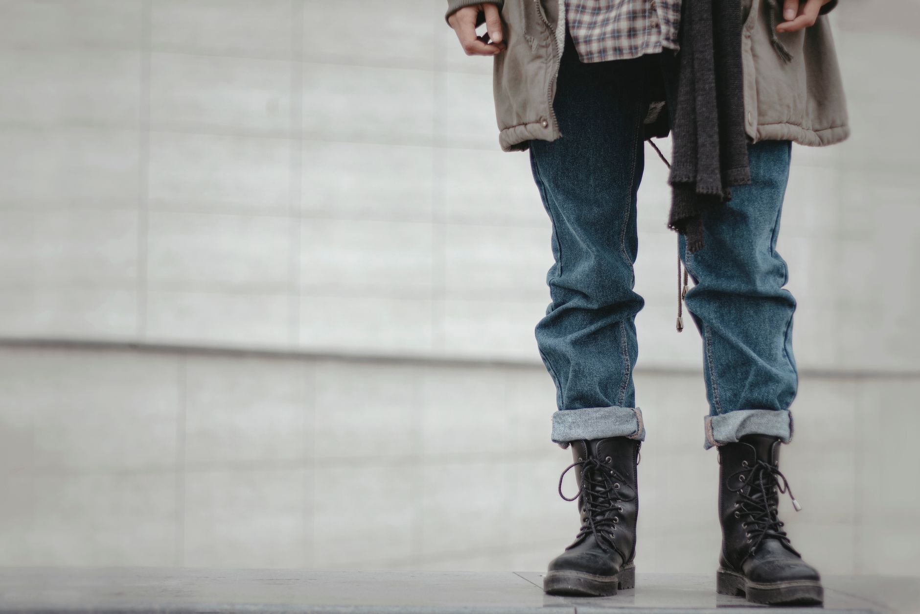 Trendy outfit featuring rolled denim jeans and black leather boots in a casual urban setting.