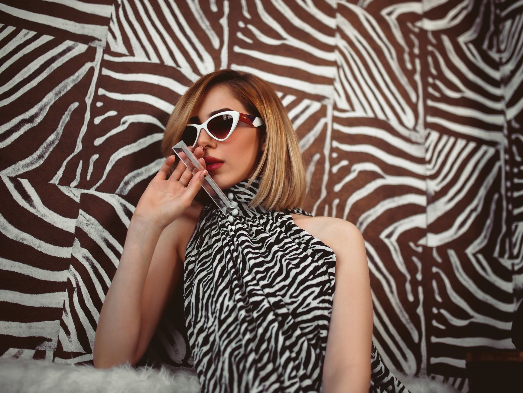 Fashionable woman wearing sunglasses and zebra print outfit, exuding a chic vibe indoors.