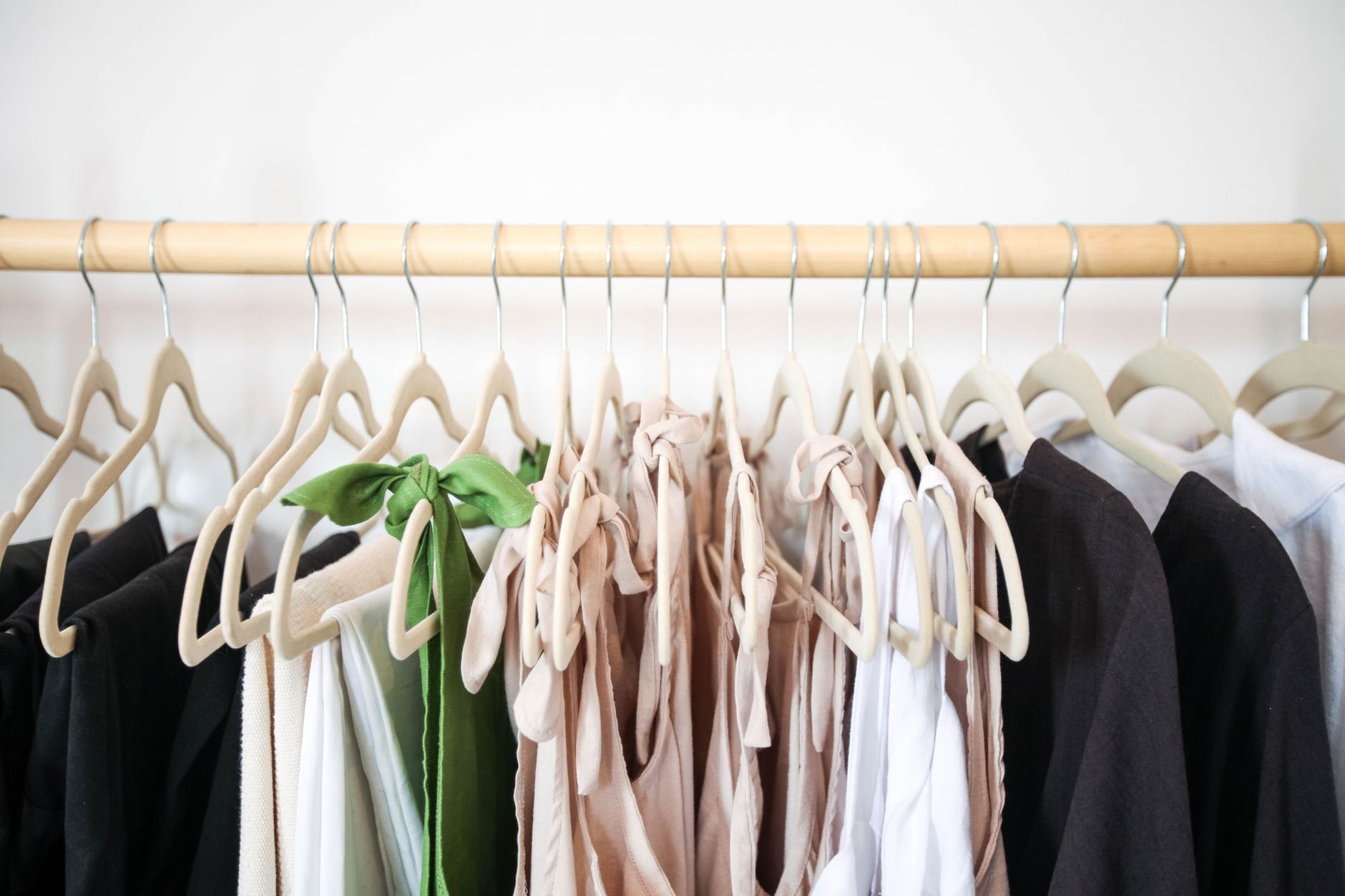 Stylish clothes beautifully arranged on a wooden hanger rack.