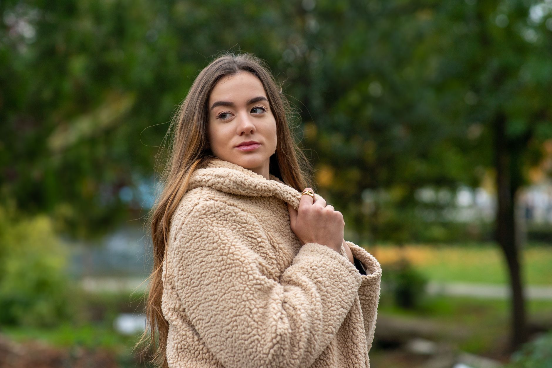Portrait of a young woman wearing a teddy coat in a Paris park during fall.