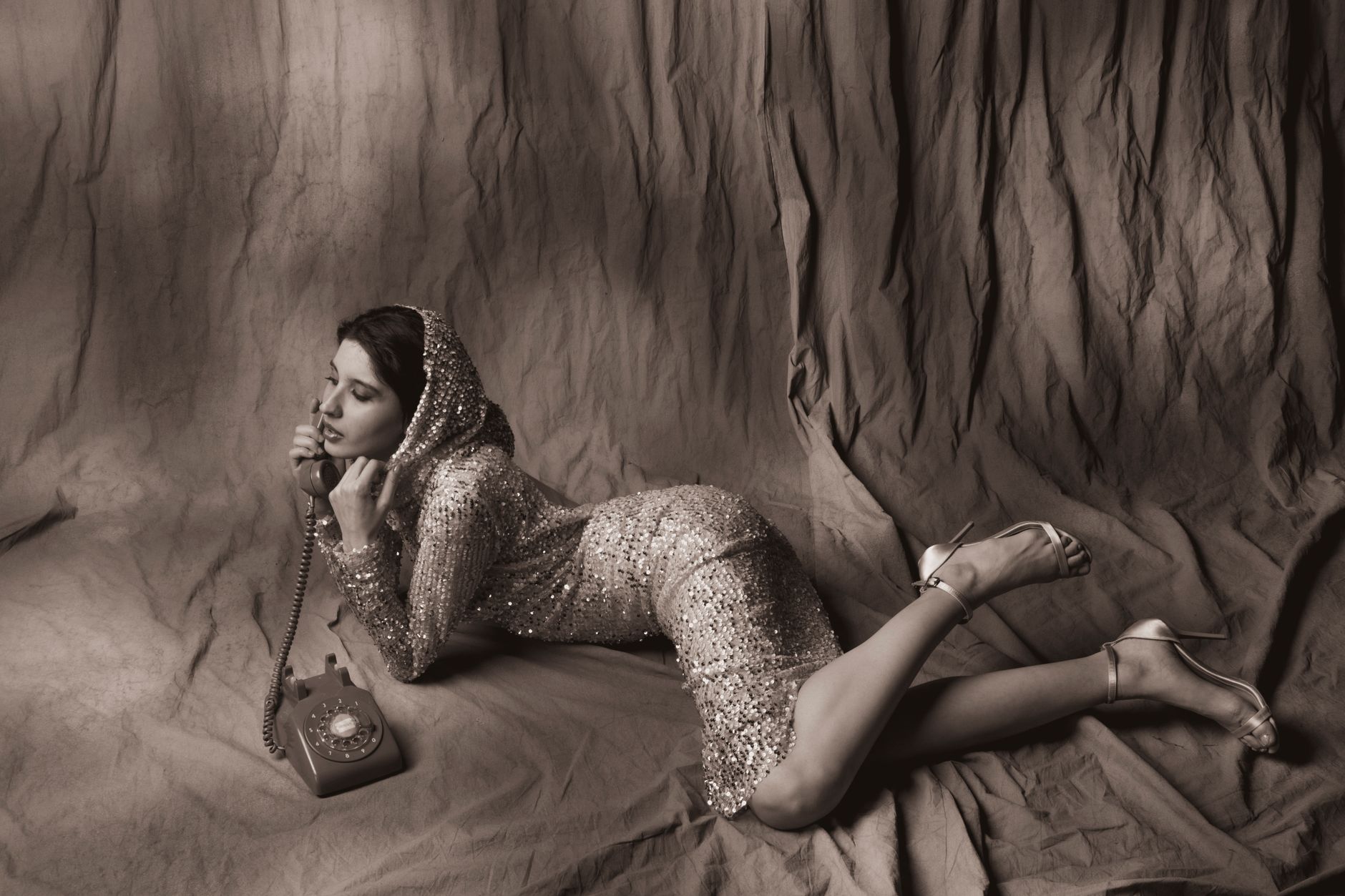 Elegant woman posing with a rotary phone in a vintage sequined dress.