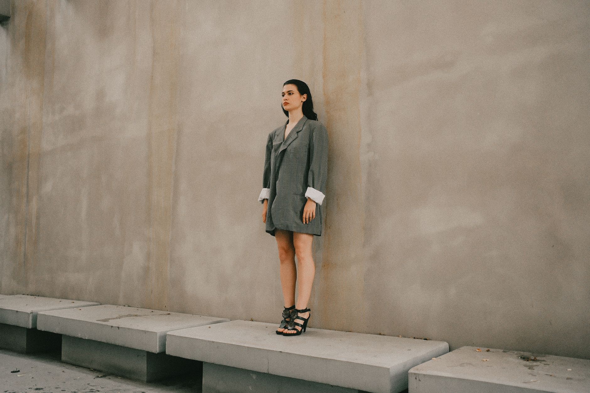 Stylish woman standing against a concrete wall, wearing an oversized blazer.