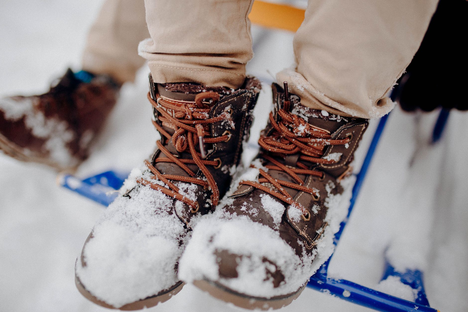 Brown winter boots covered in snow on a snowy day, capturing the essence of winter outdoors.