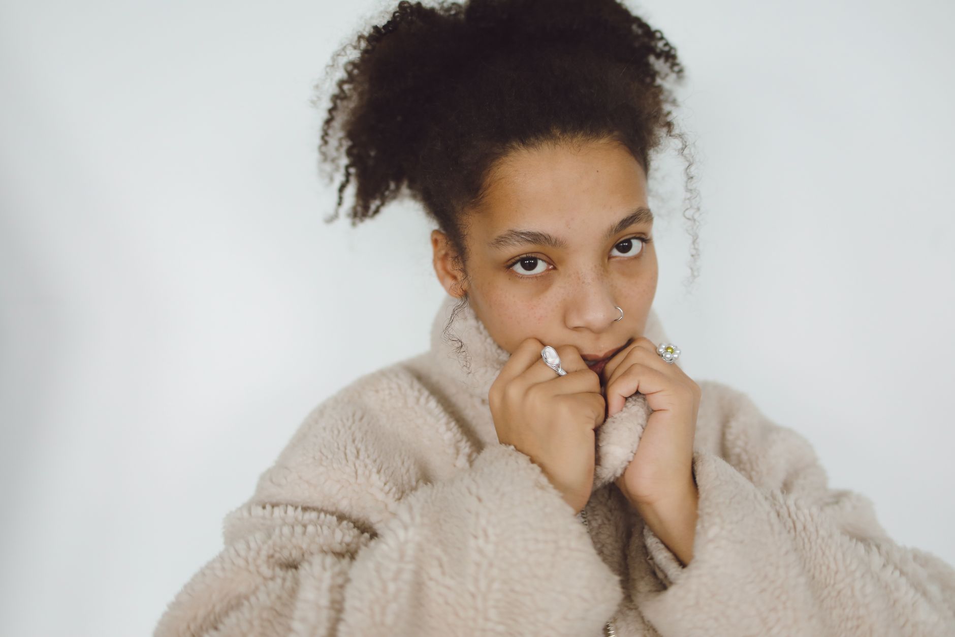A woman in a soft fur jacket poses against a neutral background.