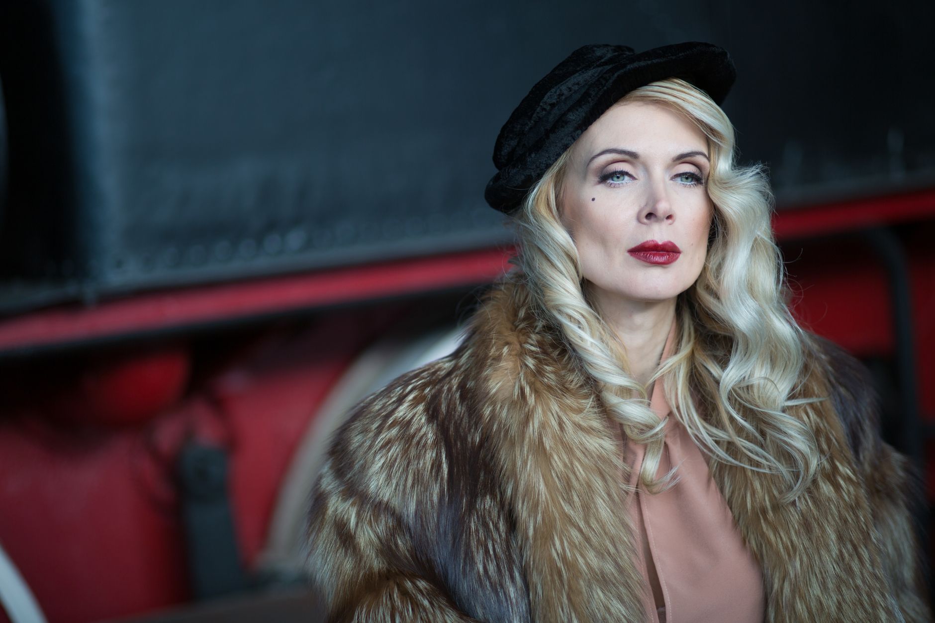 Portrait of an elegant woman with blonde hair in a fur coat and black hat, exuding vintage glamour.