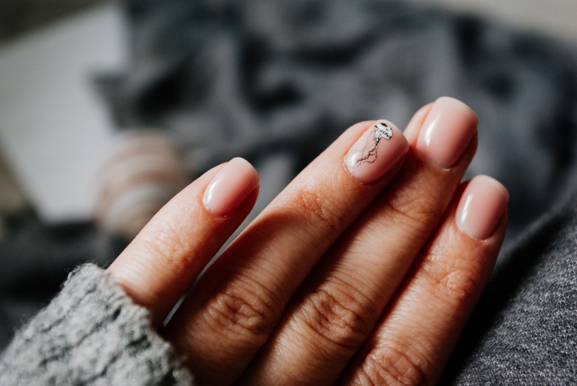 From above of crop unrecognizable female in warm sweater demonstrating hands with manicure with creative nail art